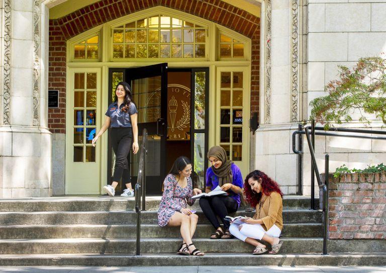 female students sit on the steps of Knoles Hall